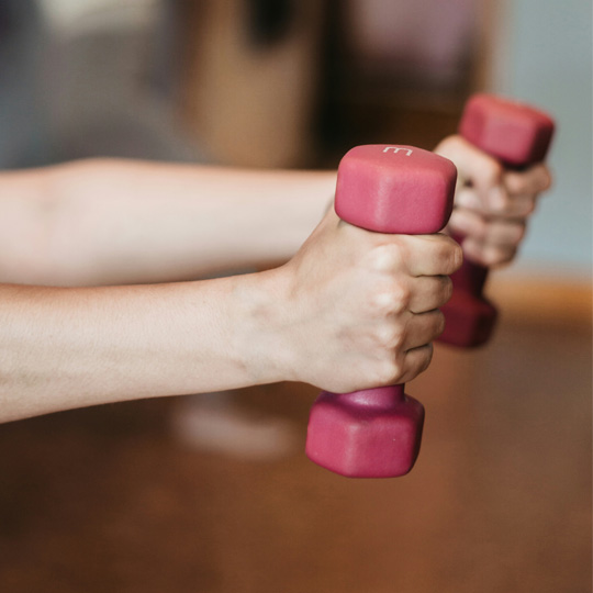 Close up shot of hands holding pink weights